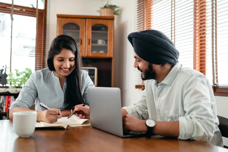 Deux adultes échangeant autour de documents et d’un ordinateur — photo d’illustration