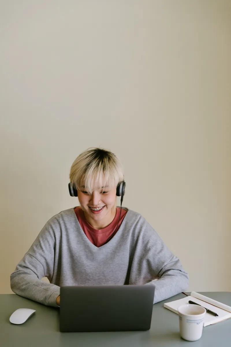 Une personne souriante avec un casque devant son ordinateur — photo d’illustration
